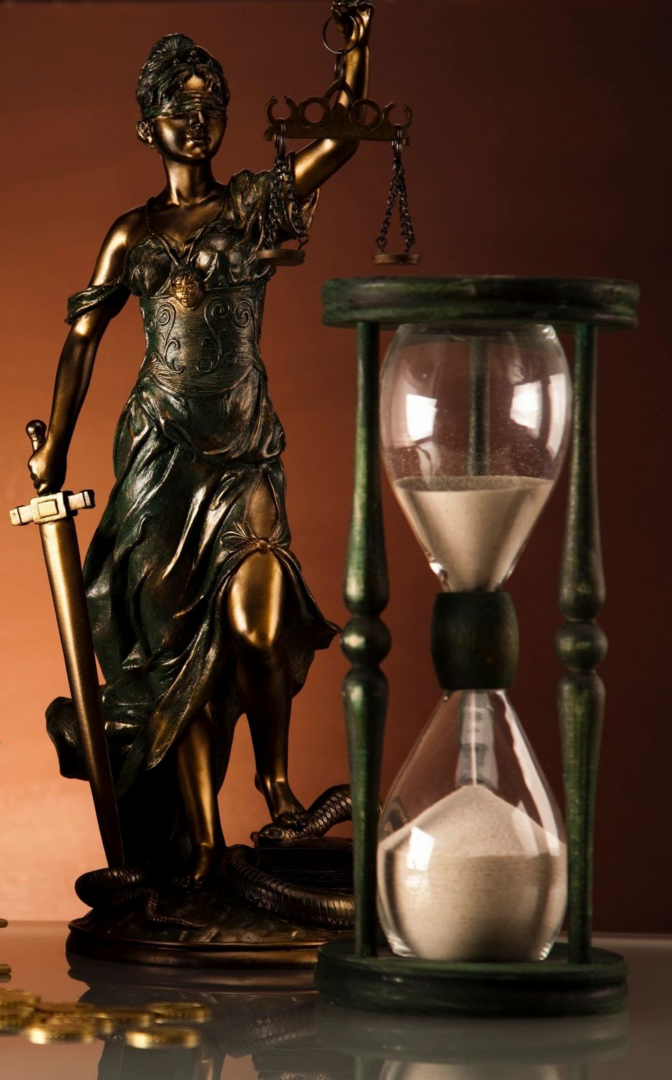 A statue of lady justice and an hourglass.