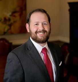 A man in a suit and tie standing next to a wall.