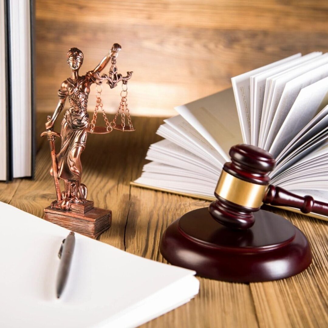 A law book, gavel and statue of justice on top of a table.